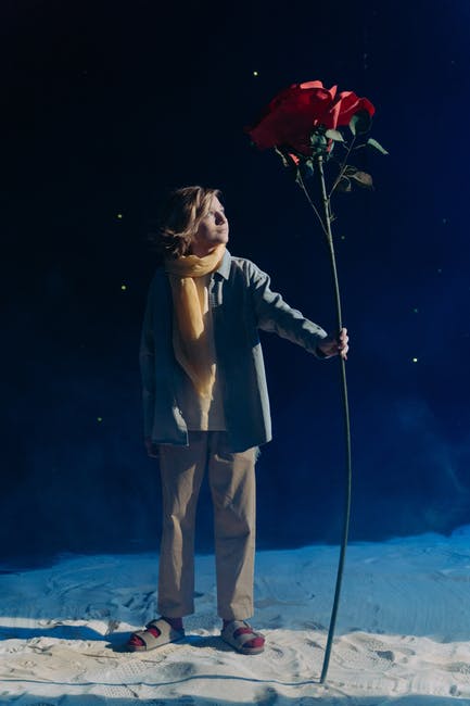 Niño disfrazado del Pequeño Principe, manteniando una rosa gigante.